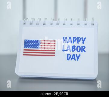 Notebook with printed text HAPPY LABOR DAY and American flag on wooden background Stock Photo