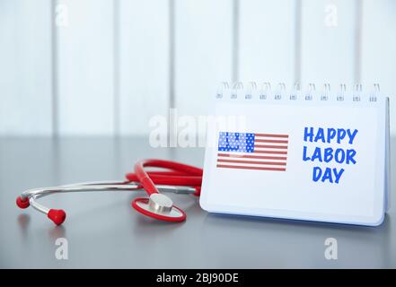 Notebook with printed text HAPPY LABOR DAY and stethoscope on wooden background Stock Photo
