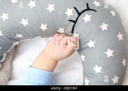 Baby hand beside pillow on bed Stock Photo