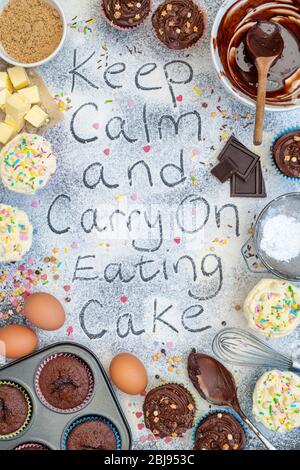 Keep calm and carry on eating cake written in flour with ingredients and cupcakes Stock Photo