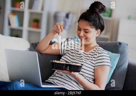 Young Asian woman eat lunch and watching something on laptop. Stock Photo