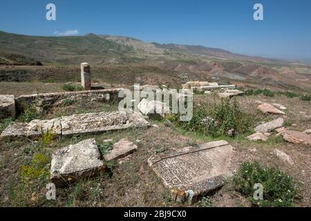 An abandoned cemetery adjacent to Ishak Pasa Palace at Dogubayazit in Turkey displaying fallen stone carved headstones. Stock Photo