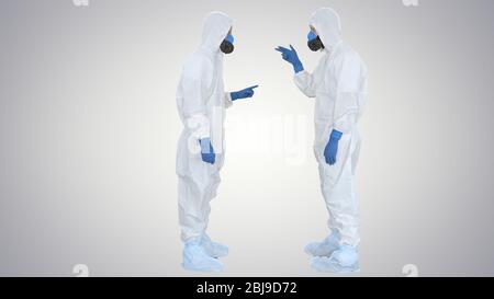 Doctors or scientists in hazamat suits meet and shake hands on gradient background. Stock Photo