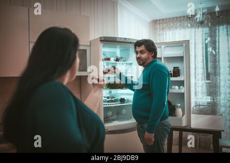 Conflict of Plus Size couple near opened refrigerator Stock Photo