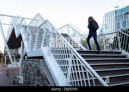 Caucasian woman wearing a protective mask and walking up the stairs Stock Photo