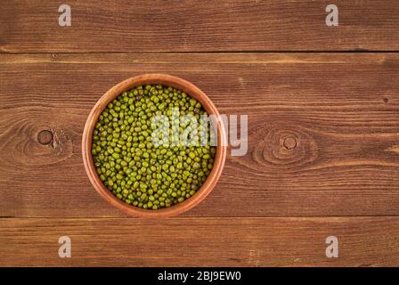 Mung beans in wooden bowl on brown background, top view, copy space Stock Photo