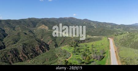 Wide green wilderness in wooded southern California hills with winding road leading through it. Stock Photo