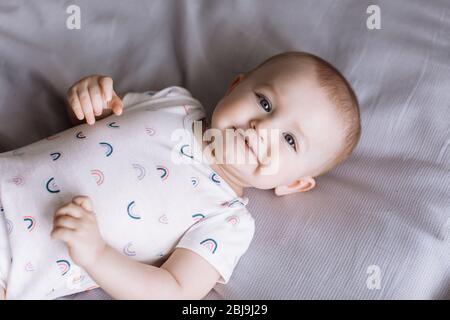 portrait of smiling baby little girl lies on bed in the bedroom at home. concept of happy childhood Stock Photo