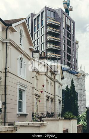 Concept photo of an old Georgian architecture style white stucco terraced houses and a new multi-story apartment building under construction on the ba Stock Photo