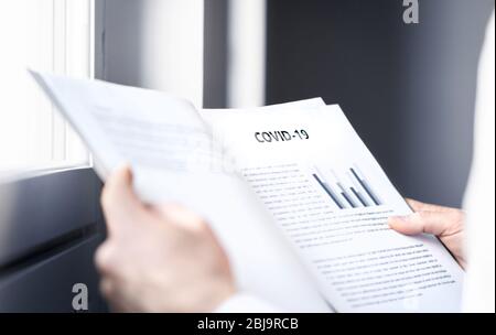 Coronavirus report about patient information or covid 19 impact on business finance market. Doctor reading virology laboratory research. Stock Photo