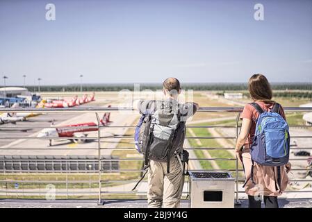 Backpackers at the airport looking at the fleet of planes parked on the runway and ready to take off. Stock Photo
