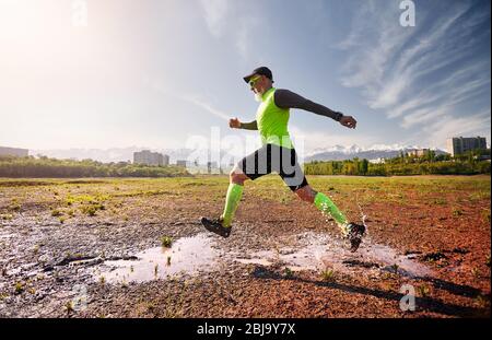 Man with grey beard running on the dirty trail at mountain background in the morning. Healthy lifestyle concept Stock Photo