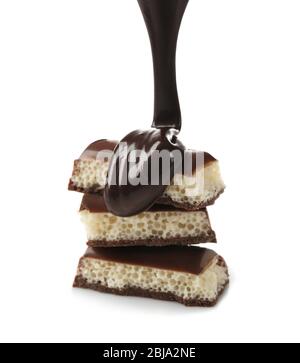Melted chocolate pouring on chocolate bar, isolated on white Stock Photo