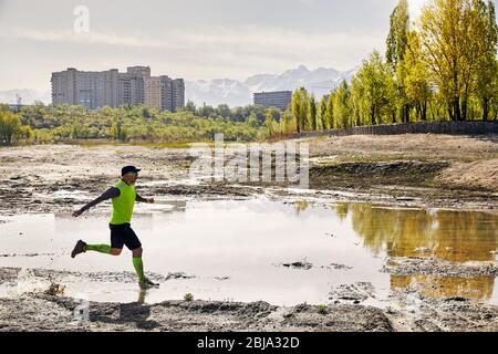 Man with grey beard running on the dirty trail with pool at mountain background in the morning. Healthy lifestyle concept Stock Photo