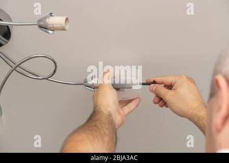 man changes a light bulb in a lighting device, lamp twist. Stock Photo
