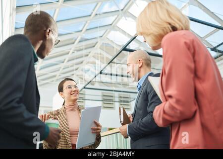 Multiethnic business team holding documents and discussing them before meeting at office Stock Photo