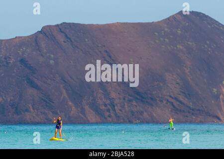 A woman paddle boarding at Corralejo with Isla de Lobos in the background, Fuerteventura, Canary Islands, Spain Stock Photo