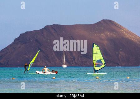Windsurfers and boats at Corralejo with Isla de Lobos in the background, Fuerteventura, Canary Islands, Spain Stock Photo