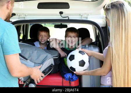 Parents putting luggage in car trunk Stock Photo