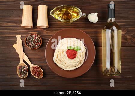Composition of spaghetti in brown plate on wooden background Stock Photo
