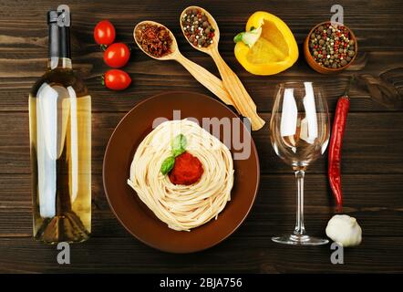 Composition of spaghetti in brown plate on wooden background Stock Photo