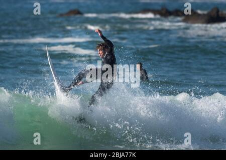 Spectacular action as a male surfer rides a wave at Fistral in Newquay in Cornwall. Stock Photo