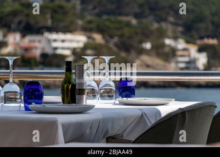 beautiful laid table in a restaurant overlooking the mediterranean sea with sant elm in the background Stock Photo