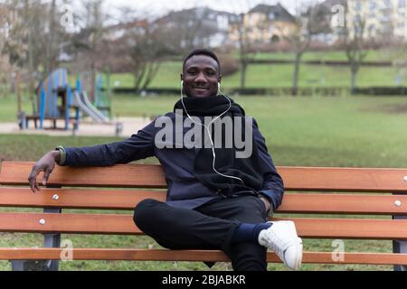 Young Black Man Leaning Back on Park Bench Confidently Stock Photo