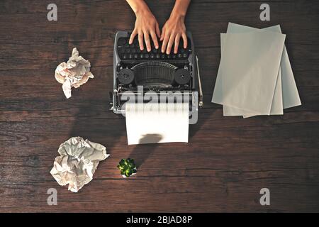 Woman hands working with retro typewriter and sheet of paper on wooden background Stock Photo
