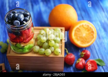 Glass jar with fruits and berries on wooden box