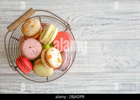 Colorful tasty macaroons in metallic bowl on light wooden background Stock Photo