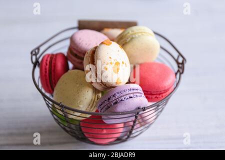 Colorful tasty macaroons in metallic bowl on light background Stock Photo