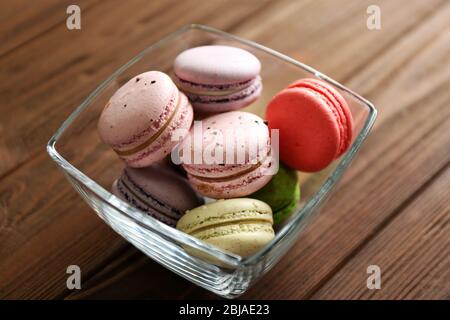 Colorful tasty macaroons in glass bowl on wooden background Stock Photo