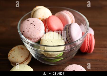 Colorful tasty macaroons in glass bowl on wooden background Stock Photo