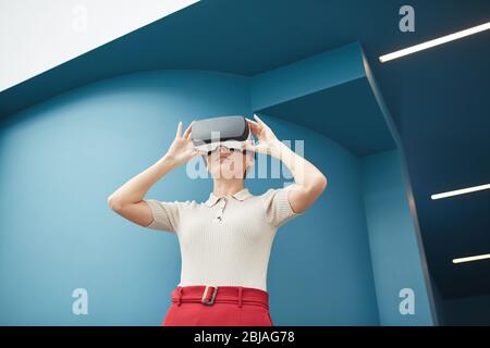 Young beautiful woman wearing virtual glasses watching some virtual reality outdoors Stock Photo