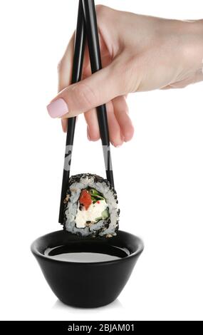 Female hand holding delicious sushi roll with chopsticks, isolated on white Stock Photo