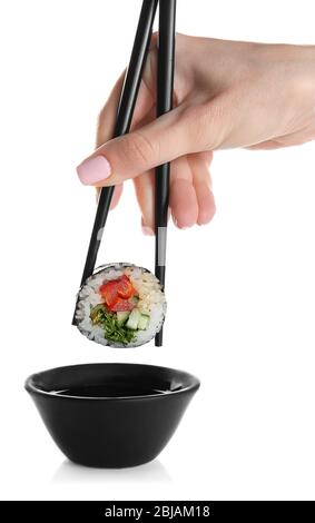 Female hand holding delicious sushi roll with chopsticks, isolated on white Stock Photo