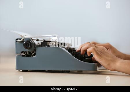 Man working on retro typewriter at desk Stock Photo