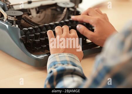 Man working on retro typewriter at desk Stock Photo