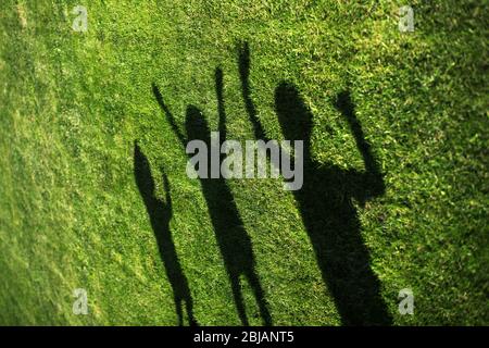 silhouettes of three persons standing with their hands stretched up Stock Photo