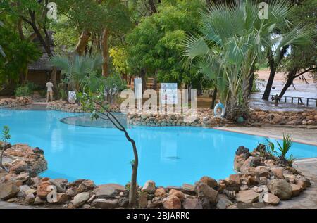 Kenya East AfricaBlu swimming pool at Sarova Shaba Game Lodge near Buffalo Springs, Kenya. Note the flooding Ewaso Nyiro river Stock Photo