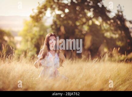 Portrait of a beautiful young woman walking through a field of tall grass. Stock Photo