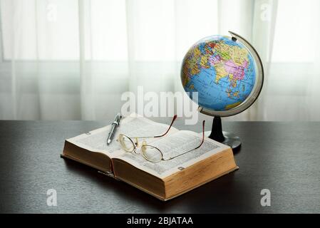 Old Book, Pen, Globe And Glasses on the Dark Table with Window Background. Stock Photo