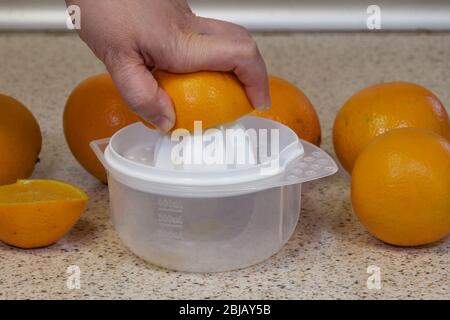 Female hand squeezing orange juice from fresh oranges with a juicer in the  home kitchen, ?lose up Stock Photo - Alamy