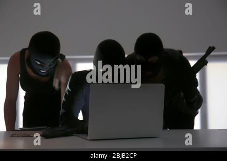 Armed thieves hacking laptop in the room Stock Photo