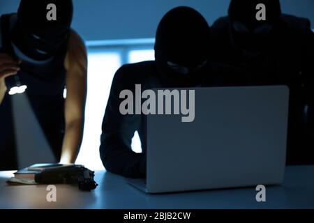 Armed thieves hacking laptop in the room Stock Photo