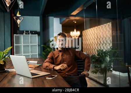Businessman working late at his desk in a dark office Stock Photo