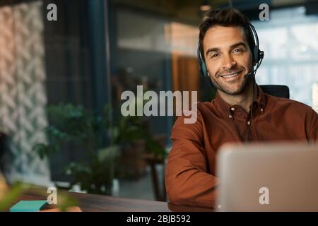 Smiling businessman talking on a headset in his office Stock Photo
