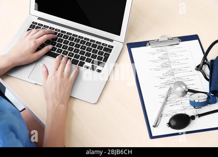 Female doctor hands typing on laptop Stock Photo