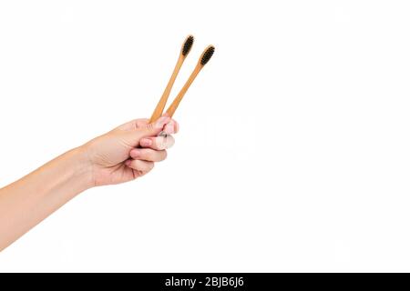 Female hand holding two bamboo eco toothbrushes isolated on white. Dental care with copy space. Stock Photo
